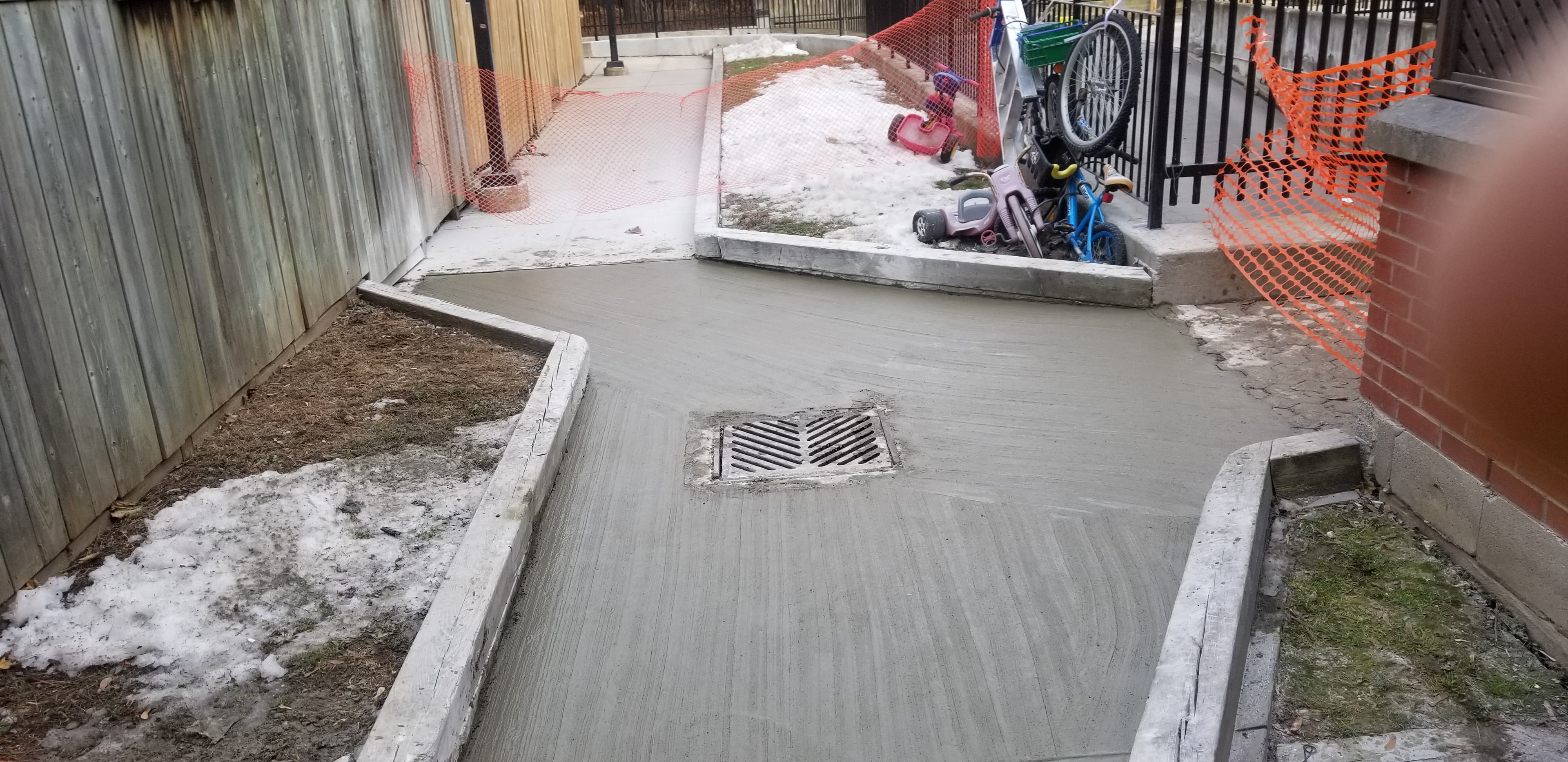 Concrete Courtyard Pour — Drain Integration & Orange Safety Fencing