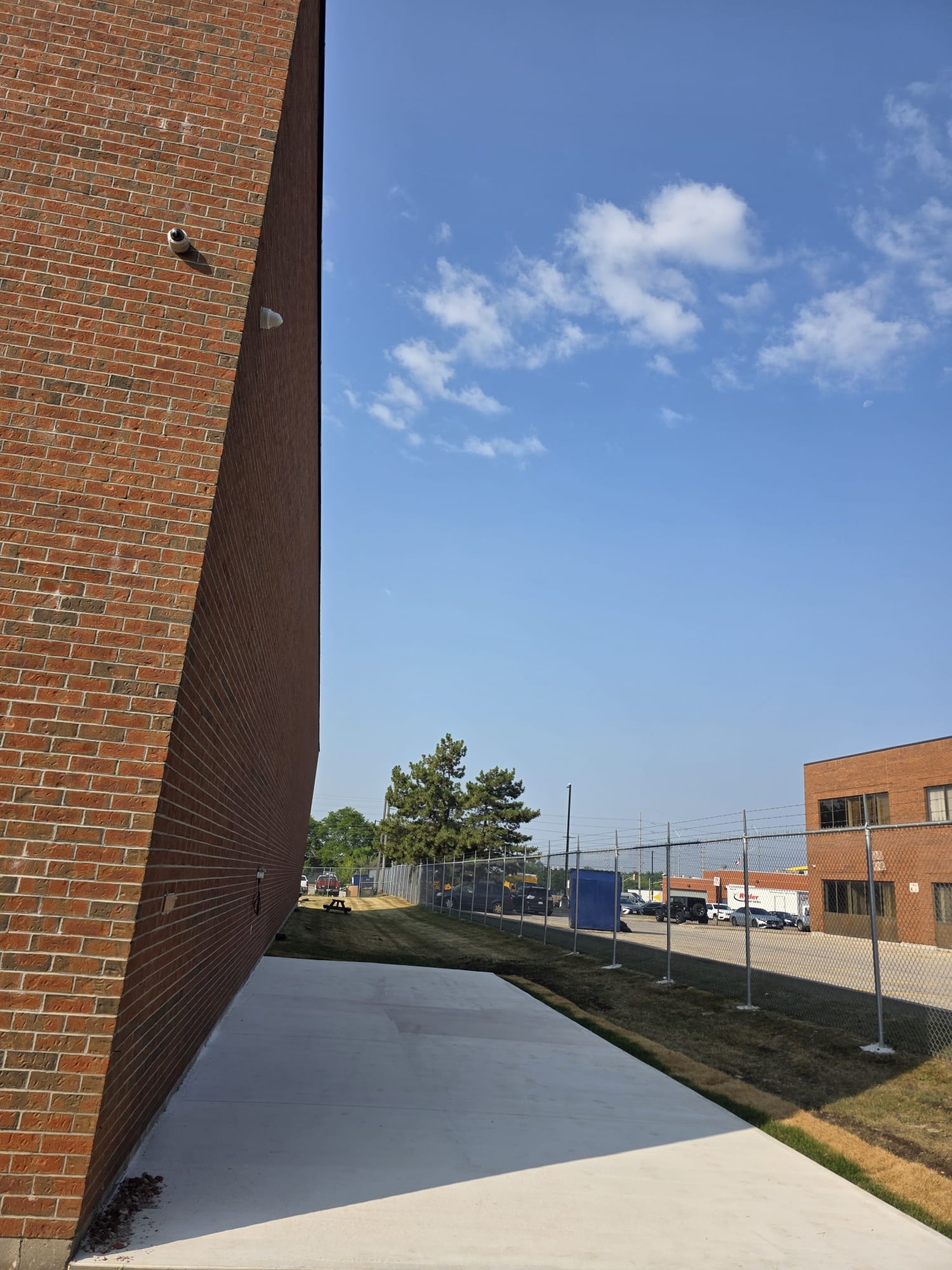 Finished Concrete Walkway — Commercial Brick Building & Chain-Link Fence