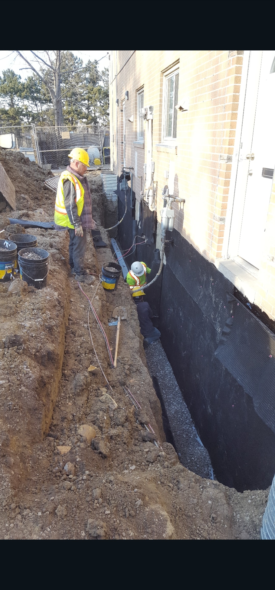 Exterior Waterproofing — Three Workers in Hard Hats & High-Vis Vests