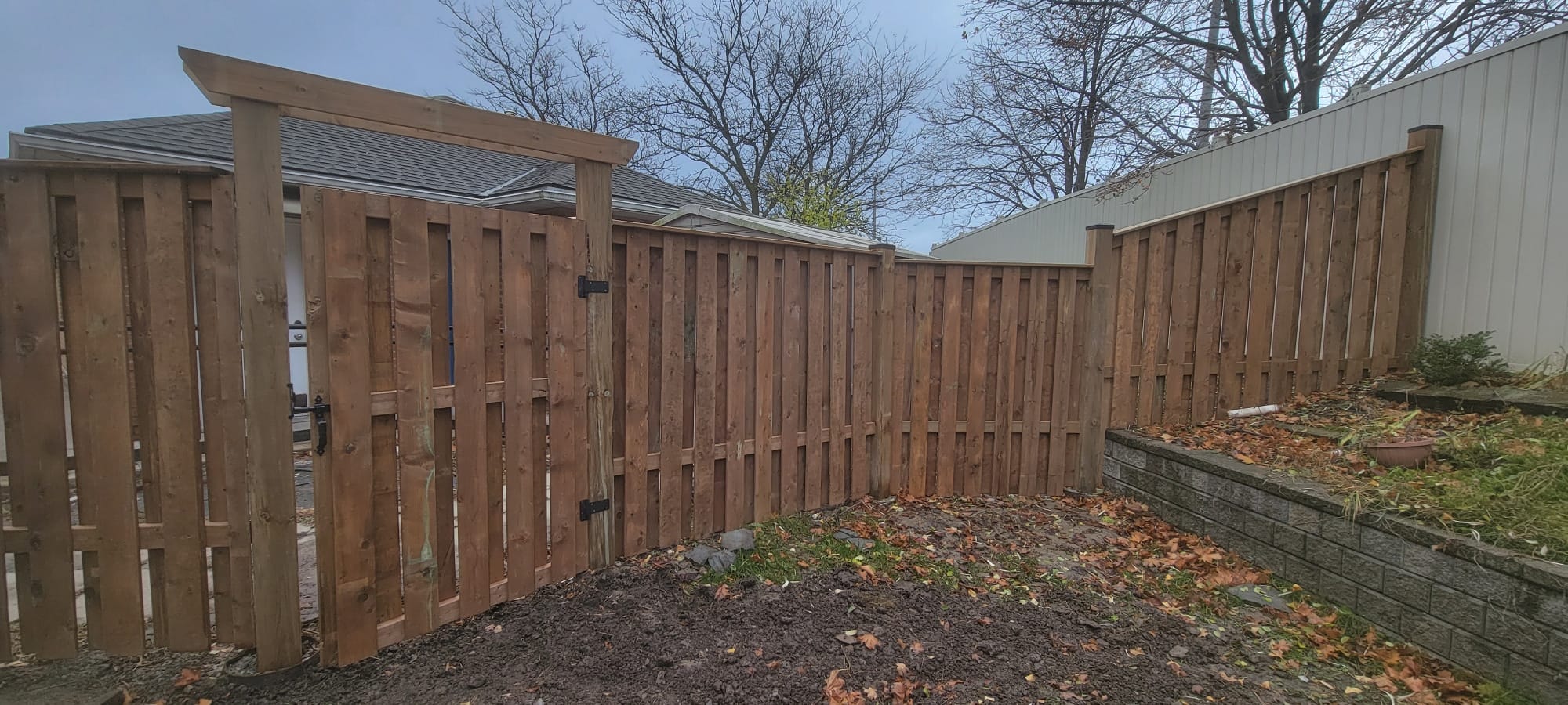 Wood Fence with Pergola Gate & Retaining Wall — Commercial Housing Unit